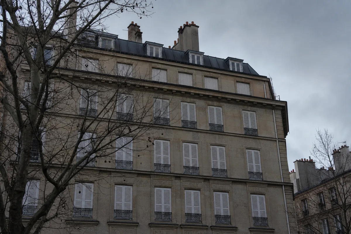 Façade d&rsquo;immeuble d&rsquo;habitation sous une lumière grise d&rsquo;hiver, volets fermés